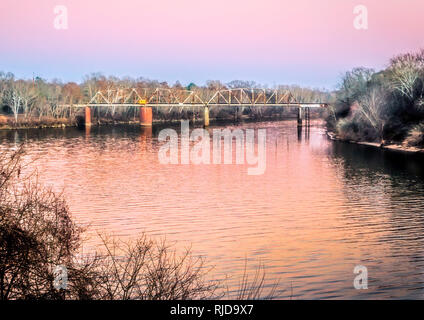 The sun sets on the CSX railroad bridge over the Alabama River, Feb. 14, 2015, in Selma, Alabama. The bridge is a Parker through truss swing bridge. Stock Photo