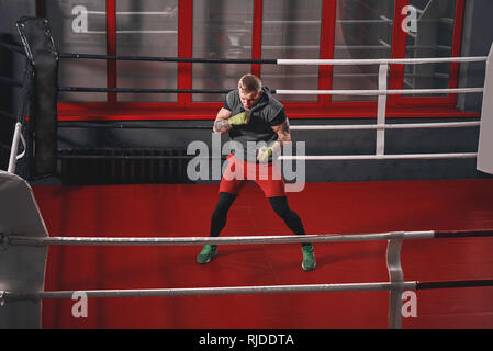 Handsome muscular sportsman in sports clothing training on red ring in the gym. Sport concept Stock Photo