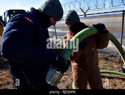 U.S. Air Force Staff Sgts. Shane Wasara and Albert Bullard, 51st Civil Engineer Squadron water and fuels system maintainers, connect a strainer to a water pump hose at Osan Air Base, Republic of Korea, Jan. 24, 2018. Members from the 51st CES had to repair an underground water line that was damaged due to cold weather. Stock Photo