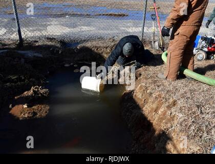 U.S. Air Force Senior Airman Jimmy Huang, 51st Civil Engineer Squadron water and fuels system maintainer, collects water using a bucket at Osan Air Base, Republic of Korea, Jan. 24, 2018. Members from the 51st CES had to repair an underground water line that was damaged due to cold weather. Stock Photo