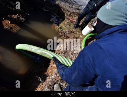 U.S. Air Force Staff Sgt. Shane Wasara, 51st Civil Engineer Squadron water and fuels system maintainer, lowers a water pump hose into a hole full of water at Osan Air Base, Republic of Korea, Jan. 24, 2018. Members from the 51st CES had to repair an underground water line that was damaged due to cold weather. Stock Photo