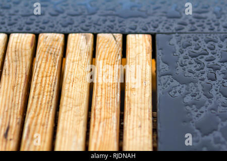 Wooden natural planks, polished boards, garden park bench with transparent big clear rain water drops on blue gray wet background. Empty place for rec Stock Photo