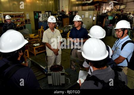 YOKOSUKA, Japan ― Hitoshi Nakamura, the electrical shop head, center left and Hideo Watanabe, the Electrical/Electronics Group Master, center right, onboard Ship Repair Facility and Japan Regional Center, explain about motor maintenance and their work during a shop tour as part of a media briefing to the Yokosuka area press hosted by U.S. Fleet Activities (FLEACT) Yokosuka, Aug. 1, 2018. FLEACT Yokosuka provides, maintains, and operates base facilities and services in support of 7th Fleet’s forward-deployed naval forces, 71 tenant commands, and 27,000 military and civilian personnel. Stock Photo