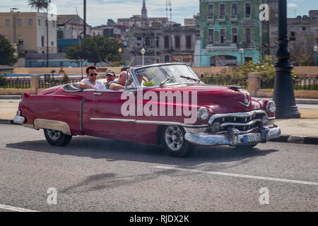 A typical old american car taxi full of tourists drives along the Malecon Embankment near the Old Town in Havana, Cuba Stock Photo