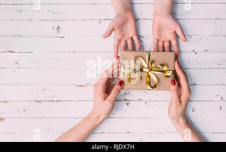 Happy women's day. Little child is congratulating mom and giving her gift on wooden background. Stock Photo