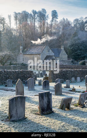 St. Mary's Church cemetery and cottages in the winter frost. Bibury, Cotswolds, Gloucestershire, England Stock Photo
