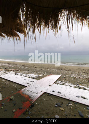 Under a straw umbrella in a Beach covered with snow in Pieria, central Macedonia  Greece Stock Photo