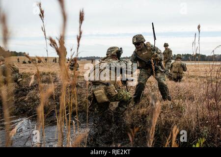 U.S. Marines wade through water and mud of flooded rice paddies during ...