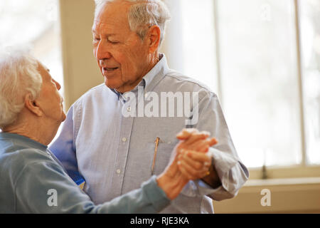Happy senior couple dancing together in a room. Stock Photo