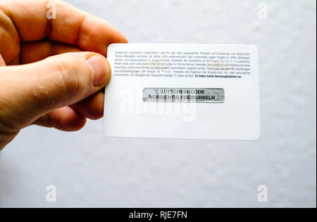 Frankfurt, Germany - Dec 28, 2018: Man hand holding rear part of an Amazon gift card with untouched scratch part Stock Photo