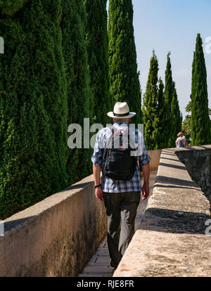 Senior man wearing Panama hat walking on outer fortified wall, Alcazaba, Malaga, Andalusia, Spain Stock Photo