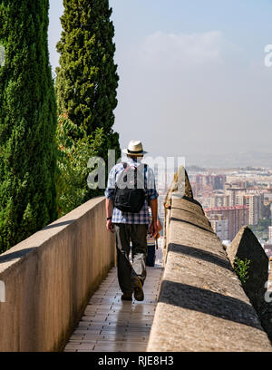 Senior man wearing Panama hat walking on outer fortified wall, Alcazaba, Malaga, Andalusia, Spain Stock Photo