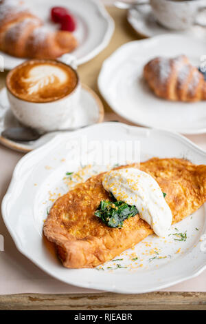 Breakfast. Frittata - italian omelet. Omelette with tomatoes, avocado, spinach and soft cheese. Croissants, coffee and other dishes on the table in Stock Photo