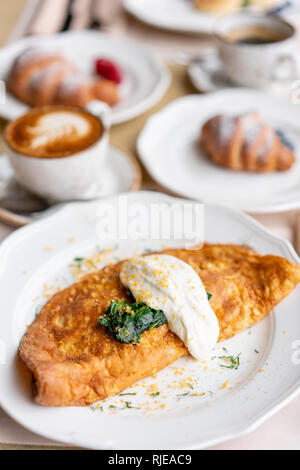 Breakfast. Frittata - italian omelet. Omelette with tomatoes, avocado, spinach and soft cheese. Croissants, coffee and other dishes on the table in Stock Photo