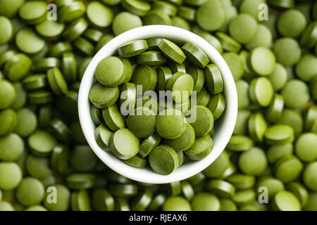 Green chlorella pills or green barley pills in bowl. Top view. Stock Photo