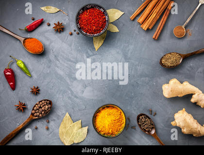 Various Spices powder turmeric, chili, bayberry, bay leaf, ginger, cinnamon, cumin, star anise on grey stone background with space for your text, shot Stock Photo