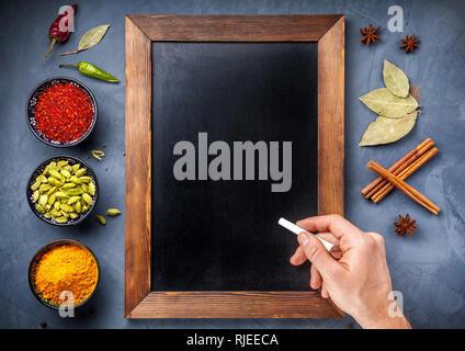 Various Spices powder turmeric, cardamom, chili, paprika, ginger, star anise and clove near blackboard  and hand with white chalk on grunge background Stock Photo