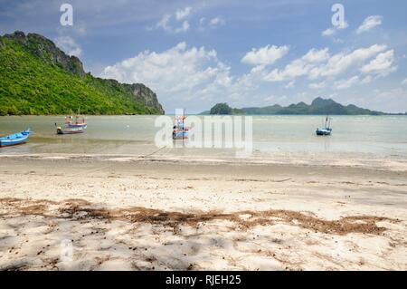 Thai longtail fishing boats on sandy beach in Ao Manao bay during low tide in Prachuap Khiri Khan province of Thailand Stock Photo