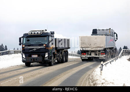 Salo, Finland - February 2, 2019: Two Volvo tipper trucks meet on a bridge during busy snow haul away from city to municipal snow dumping area. Stock Photo