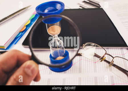 Hourglass. Businessman working in the office in the background. Concept time is money. Stock Photo