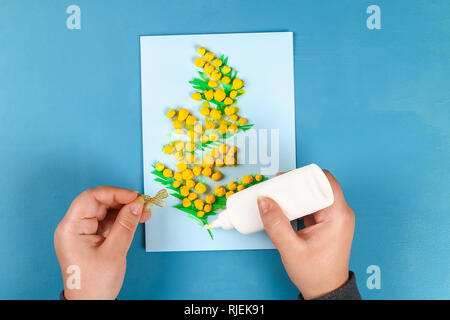 Diy greeting card with mimosa flowers paper balls for March 8 on blue background. Gift idea, decor International Womens Day, March 8, Mother day. Step Stock Photo