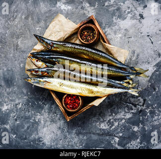 Appetizing smoked fish on kitchen board.Smoked saury.Smoked fish with spices Stock Photo