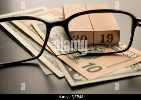 Glasses, number 2019 on the dollar banknotes background. Selective focus Stock Photo