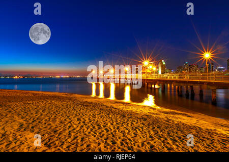 Scenic night view with full moon at Coronado ferry landing in Coronado Island, California, USA. Downtown of San Diego on background. Old wooden pier Stock Photo
