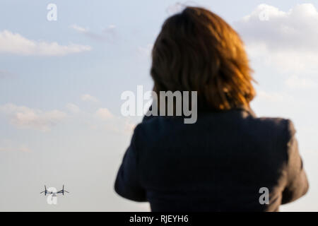 A Japanese woman watches the controversial Bell Boeing V22 Osprey tilt-rotor aircraft with the US Marines, taking off from Naval Air Facility Atsugi, Japan Stock Photo
