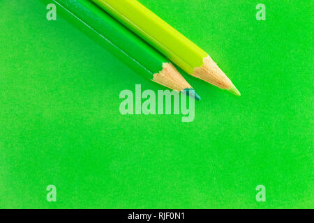 Two green  pencils on a colored  background , light green and dark green on a green background ,beautiful monochromatic effect Stock Photo