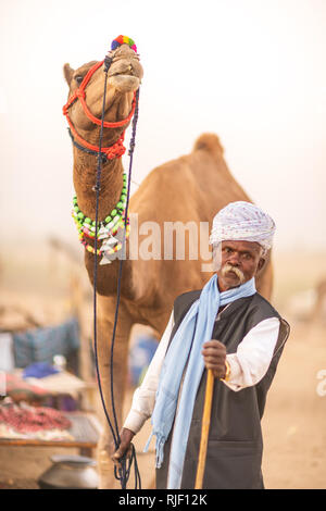 Indian men and his camel in desert Thar during Pushkar Camel Mela near holy city Pushkar. This fair is the largest camel trading fair in the world. Stock Photo