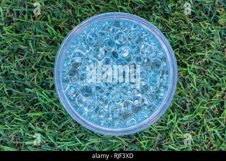 Blue gel balls in the middle on green artificial grass background. Stock Photo