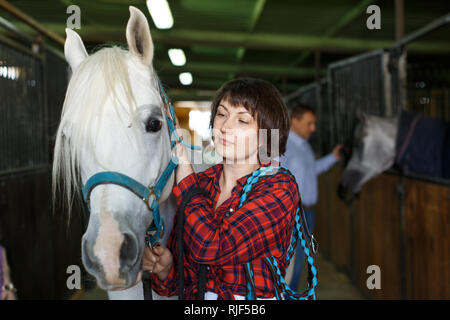Portrait of young attractive woman who works at horse stable Stock Photo