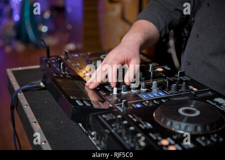 Men's hands press the buttons on the DJ remote, it makes music . DJ's hands at the music mixer at a party - playing some fine songs for the guests Stock Photo