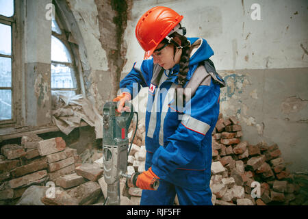 Destroying gender stereotypes. Woman wearing helmet using different male work tools. Gender equality. Girl working at flat remodeling. Building, repair and renovation. woman in the male profession Stock Photo