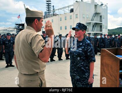 Petty Officer 3rd Class Hollie Davison, machinist's mate, repeats the oath of re-enlistment to Rear Adm. Paul Bushong, commander of Joint Region Marianas during an all-hands call for the presentation of the Chief of Naval Operations Afloat Safety Award aboard the submarine tender USS Frank Cable. Frank Cable is undergoing upgrades at Guam Shipyard as part of the Military Sealift Command conversion. Stock Photo