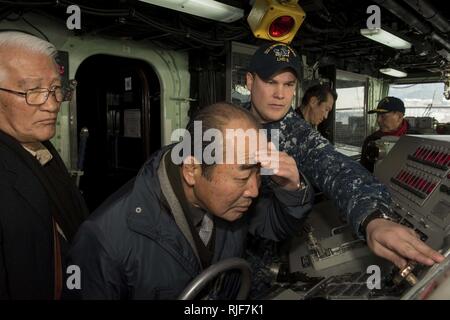 SASEBO, Japan (Jan. 18, 2017) Quartermaster 1st Class Matthew Lenerville, from Richardton, N.D., explains bridge equipment on board amphibious assault ship USS Bonhomme Richard (LHD 6) during a tour for Sasebo and Saga city community leaders. Bonhomme Richard, forward-deployed to Sasebo, Japan, is serving forward to provide a rapid-response capability in the event of a regional contingency or natural disaster. Stock Photo