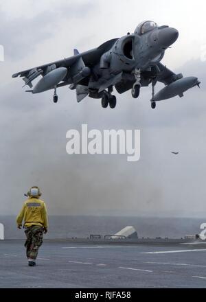 SOUTH CHINA SEA (April 29, 2008) Aviation Boatswain's Mate (Handling) 3rd Class Quoc Nguyen looks on as an AV-8B Harrier, assigned the 'Nightmares' of Marine Attack Squadron (VMA) 513, lands aboard the flight deck of the forward-deployed amphibious assault ship USS Essex (LHD 2). Essex is the lead ship of the only forward-deployed amphibious force. U.S. Navy Stock Photo