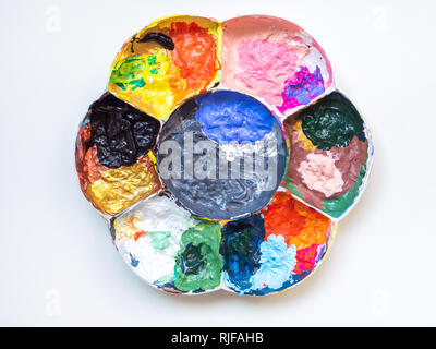 Many acrylic paint color in plastic white art palette isolate on white background. Flower shape palette top view. Stock Photo