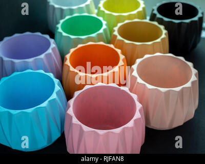 Colorful concrete planters on dark background. Painted concrete planters for home decoration. Stock Photo