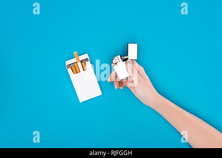Partial view of woman holding cigarette lighter in hand isolated on blue Stock Photo