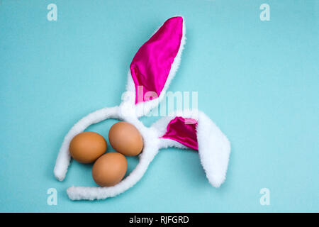 top view brown eggs  with bunny ears on a vibrant blue background Stock Photo