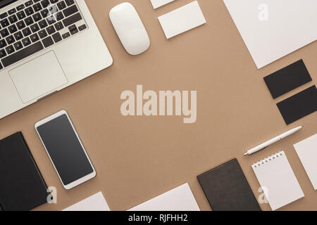 Laptop, smartphone, pen, computer mouse, cards and notebooks on beige background Stock Photo