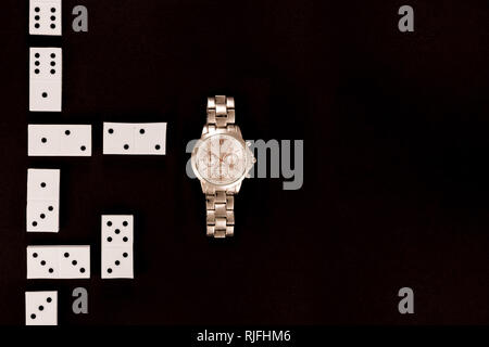 top view of luxury wristwatch lying near dominoes isolated on black Stock Photo