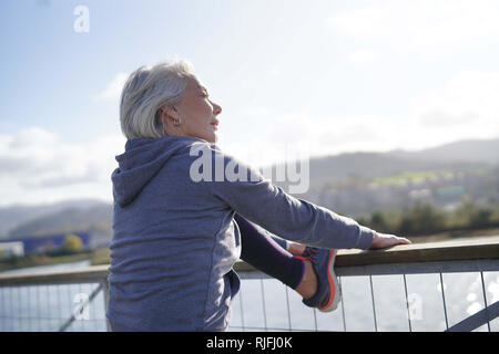 Flexible senior woman stretching outdoors after jog Stock Photo