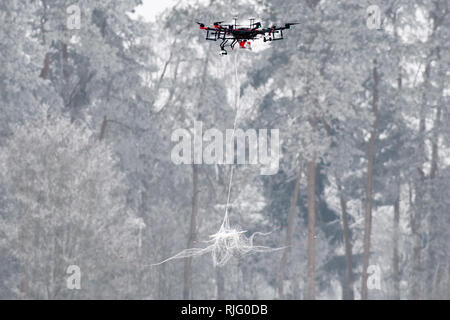 Manching, Germany. 06th Feb, 2019. An AirRobot AR200 fighter drone drops a net over a commercial small drone on a German Armed Forces presentation day to track down and fend off drones. During a presentation day at the Manching airfield near Ingolstadt, it will be demonstrated how the flying objects can be detected, forced to an emergency landing with interference radiation or taken down from the sky with an interceptor drone. Credit: Matthias Balk/dpa/Alamy Live News Stock Photo