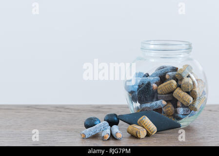 Different kinds of salmiakki candy in small jar and on table Stock Photo