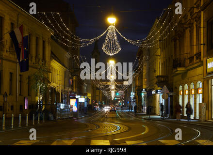 Streets of Zagreb with twisting tram tracks, illuminated with hanging christmas light, long exposure to blur movement. Stock Photo
