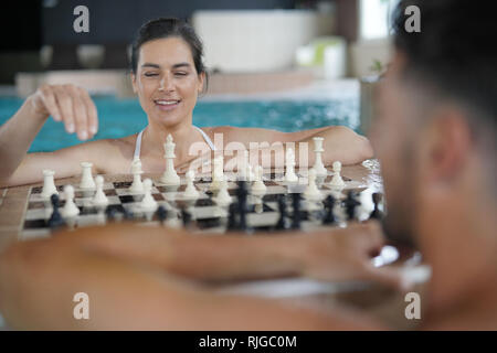 Couple playing chest in swimming-pool Stock Photo