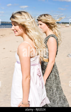 Young women standing on beach and looking at sea Stock Photo